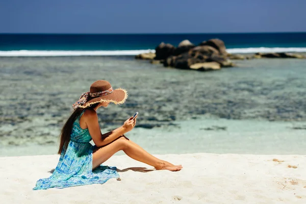 在热带地区的海滩上使用智能手机的豪华妇女 塞舌尔海滩上的女性旅行和使用智能手机 — 图库照片