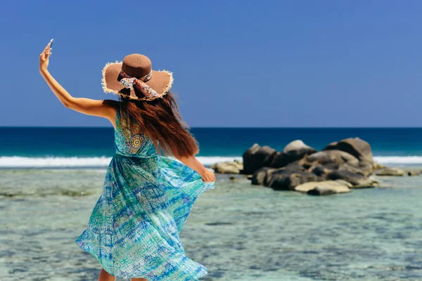 tropik plajda Smartphone tutan mutlu kadın. Erkek seyahat ve smartphone Seyşeller plaj üzerinde kullanın.