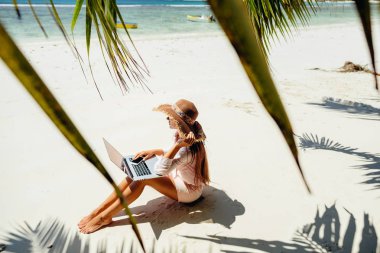 sahilde dizüstü bilgisayar ile serbest kadın. Internet üzerinden dizüstü bilgisayarda uzaktan çalışıyor. Seyahat ederken çalışmak. Seyşeller'de yaz tatili.