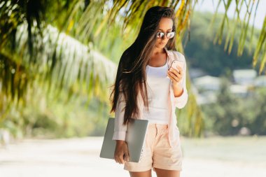 Sahilde uzaktan çalışan kadın. Seksi kadın uzaktan internet üzerinden dizüstü bilgisayarda çalışma. Seyahat ederken çalışma. Yaz tatili de Seyşeller.