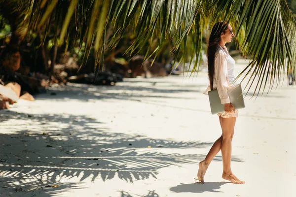 Женщина путешествует с ноутбуком на пляже в тропиках — стоковое фото