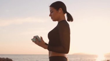 Telefon ve kulaklıkla müzik dinleyen sportif kız eğitimi.