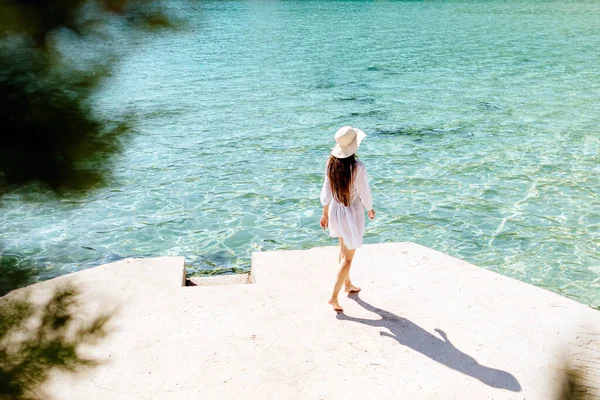 Frau in Sommerkleid und Hut spazieren am Strand — Stockfoto