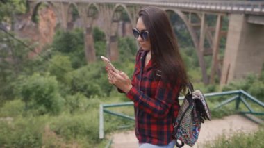 Kadın cep telefonuna bakıyor ve kırsal kesimde mesajlaşıyor.