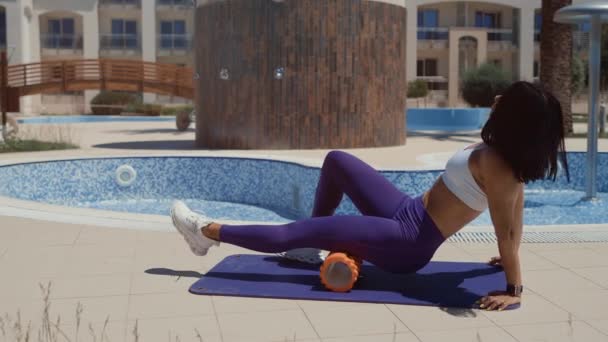 Sportslig kvinne som strekker seg og trener med skumruller – stockvideo