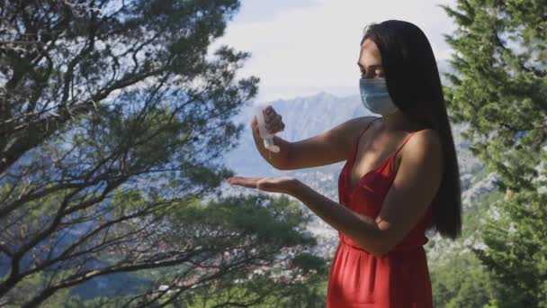 Mujer usando desinfectante de manos y usando mascarilla al aire libre en las montañas — Vídeo de stock