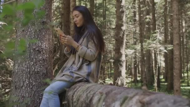 Mooie vrouw met behulp van smartphone in het bos buiten — Stockvideo