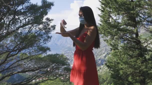 Woman using hand sanitizer and wearing face mask outdoors in mountains — Stock Video