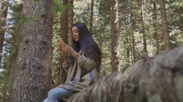Attractive woman browsing smartphone in forest outdoors — Stock Video