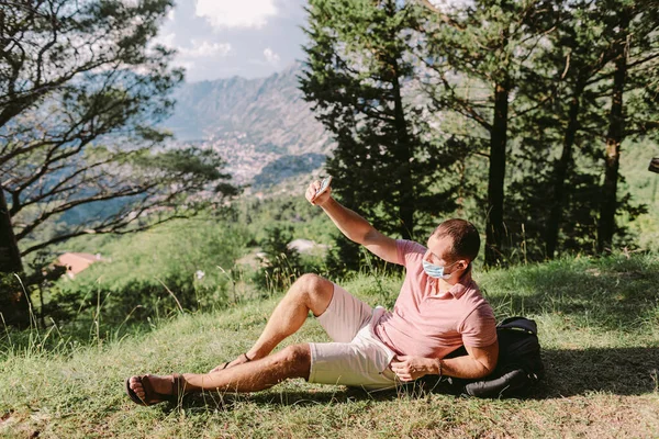 Muž cestování nosit ochrannou masku obličeje a pomocí smartphone v horách — Stock fotografie