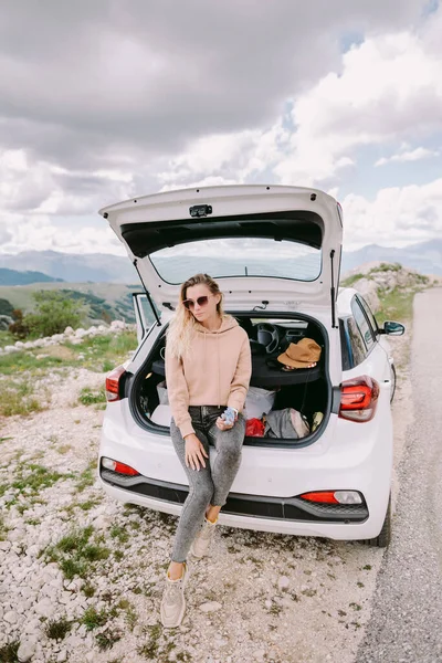 Wanita tersenyum santai di mobil mengemudi di pegunungan — Stok Foto