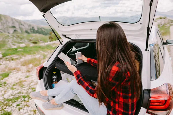 Mujer viajero cargando smartphone con powerbank en las montañas —  Fotos de Stock