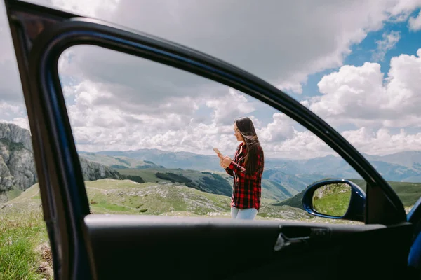 Wanita cantik wisatawan menggunakan smartphone dan perjalanan dengan mobil di pegunungan — Stok Foto