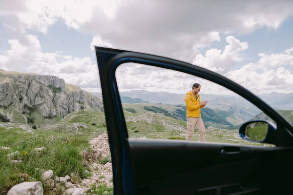 man travel by car and using smartphone in mountains