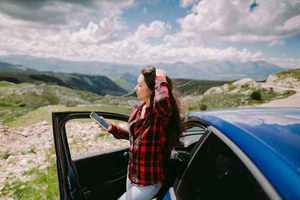 Wanita cantik wisata perjalanan dengan mobil dan browsing smartphone di pegunungan — Stok Foto
