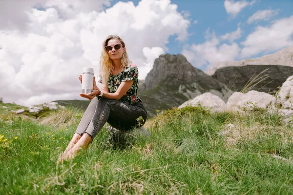 Wanita cantik memegang cangkir teh dan melakukan perjalanan di pegunungan pada liburan — Stok Foto