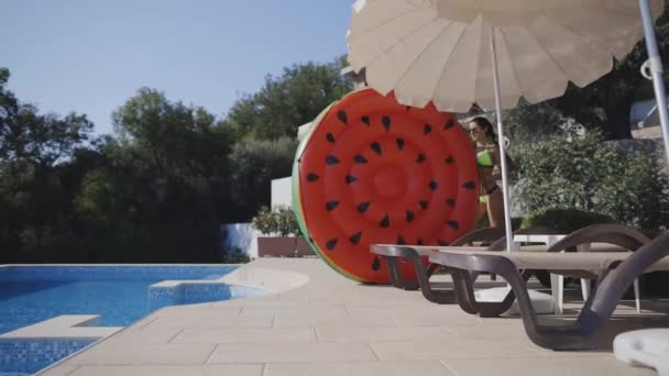 Attraktive Frau hat Spaß im Schwimmbad beim Werfen aufblasbarer Matratzen — Stockvideo