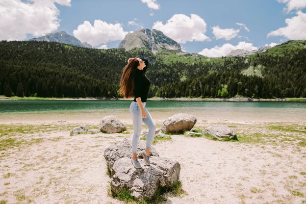 Çekici bir kadın dağlarda dinlenir göl manzaralı tatillerde — Stok fotoğraf