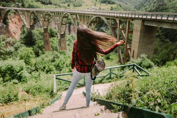 Güzel kadın gezgin köprü manzaralı kırsal alanda rahatlıyor. — Stok fotoğraf