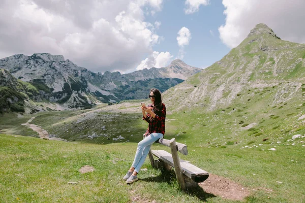 Женщина путешественник расслабиться в сельской местности и использовать смартфон в горах — стоковое фото
