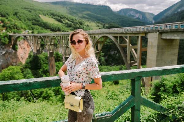 Tatillerde dağlarda kahve kupası tutan bir kadın. — Stok fotoğraf