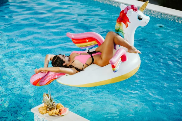 Wanita seksi berbaring di karet pantai mengapung mainan unicorn di kolam renang — Stok Foto