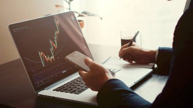 Yatırım borsacısı dizüstü bilgisayar ve telefon kullanarak bitcoin fiyat eğilimi hareketini öngörüyor