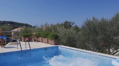 Çocuklu bir adam suya atlayıp sıçrıyor. 