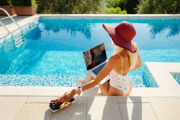Wanita pengusaha wanita seksi menggunakan laptop dan bersantai di kolam renang — Stok Foto