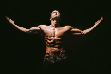 Siyah arka planda poz veren kaslı vücut adamı.