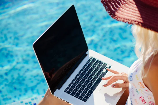 Žena pomocí notebooku a práce na dálku v blízkosti bazénu — Stock fotografie