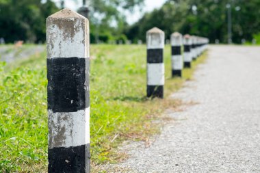 Kilometre taşları - yeşil çim yol kenarı, ağaçlar yol kenarı arka plan ile siyah ve beyaz kilometre taşları. bir sonraki adım için kavram. Bir sonraki istasyon. Düzey yukarı.