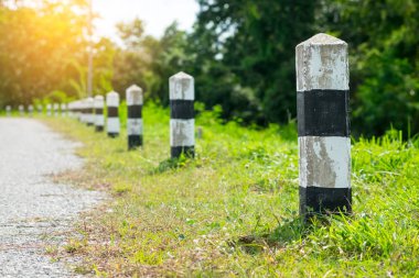 Kilometre taşları - yeşil çim yol kenarı, ağaçlar yol kenarı arka plan ile siyah ve beyaz kilometre taşları. bir sonraki adım için kavram. Bir sonraki istasyon. Düzey yukarı.