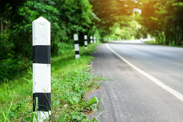 Siyah ve beyaz kilometre taşları yeşil çim yol kenarı, ağaçlar yol kenarı arka plan ile. bir sonraki adım için kavramı.