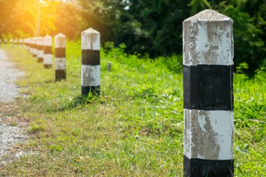 Kilometre taşları - yeşil çim yol kenarı, ağaçlar yol kenarı arka plan ile siyah ve beyaz kilometre taşları. bir sonraki adım için kavram. Bir sonraki istasyon. Düzey yukarı.