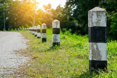 Kilometre taşları - yeşil çim yol kenarı, ağaçlar yol kenarı arka plan ile siyah ve beyaz kilometre taşları. bir sonraki adım için kavram. Bir sonraki istasyon. Düzey yukarı.