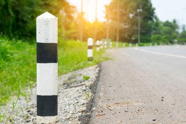 Siyah ve beyaz kilometre taşları yeşil çim yol kenarı, ağaçlar yol kenarı arka plan ile. bir sonraki adım için kavram. Bir sonraki istasyon. Düzey yukarı.