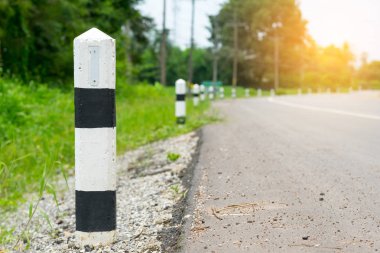 Siyah ve beyaz kilometre taşları yeşil çim yol kenarı, ağaçlar yol kenarı arka plan ile. bir sonraki adım için kavram. Bir sonraki istasyon. Düzey yukarı.