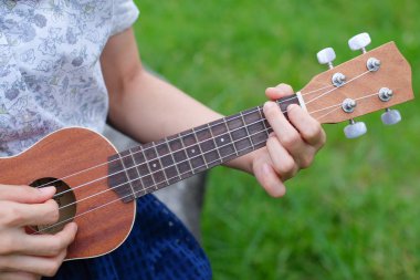 Closeup el yakalamak ukulele gitar akorları yeşil çim zemin üzerine.