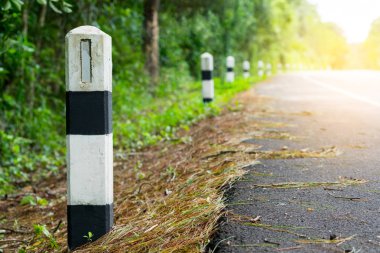 Siyah ve beyaz kilometre taşları yeşil çim yol kenarı, ağaçlar yol kenarı arka plan ile. bir sonraki adım için kavram. Bir sonraki istasyon.