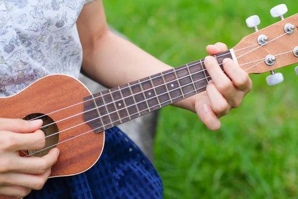 Closeup el yakalamak ukulele gitar akorları yeşil çim zemin üzerine.