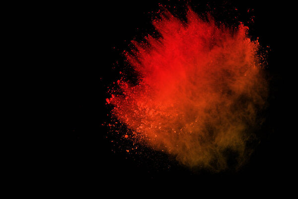 orange powder explosion isolated on black background. Freeze motion of colored dust splatted.
