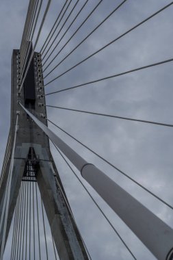 Simetrik kablo destekli köprü pilonu ve yayılan çizgiler dinamik kentsel geometri oluşturur.