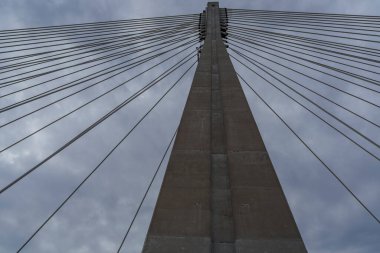 Simetrik kablo destekli köprü pilonu ve yayılan çizgiler dinamik kentsel geometri oluşturur.