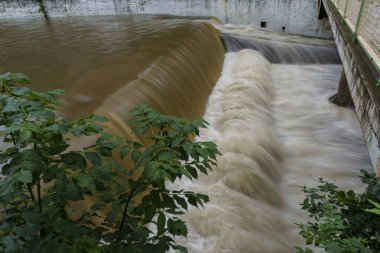 Dinamik kentsel ortamda insan yapımı baraj üzerinde hızlı akan su çağlayanı.