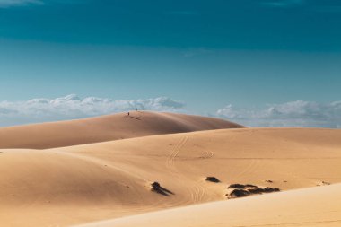 Uzaktaki grup insanları çöldeki bir tepenin üzerinde yürüyorlar..