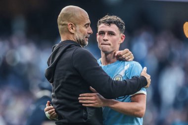 Manchester City 'nin Pep Guardiola teknik direktörü Premier League maçından sonra Manchester City Manchester United ile Etihad Stadyumu' nda 14 Eylül 2025 'te oynanan maçtan sonra Manchester City' den Phil Foden 'ı kucaklıyor.