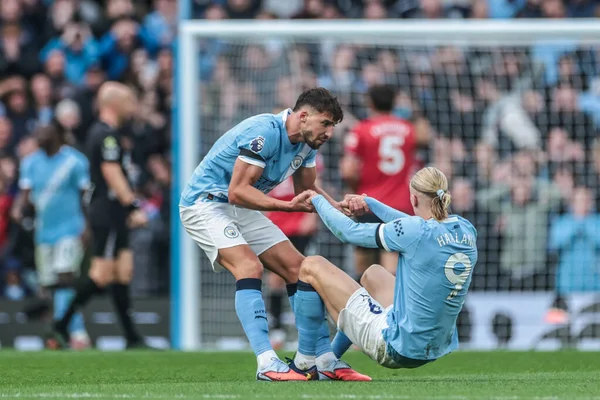 Manchester City 'den Ruben Dias Manchester City' nin Manchester United 'a karşı 14 Eylül 2025' te Etihad Stadyumu 'nda oynadığı Premier League maçında Manchester City' den Erling Haaland 'a sahadan kalkmasında yardım ediyor.