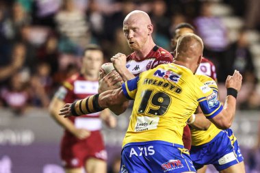 Liam Farrell of Wigan Warriors is tackled by Tom Holroyd of Leeds Rhinos during the Betfred Super League round 27 match Wigan Warriors vs Leeds Rhinos at The Brick Community Stadium, Wigan, United Kingdom, 19th September 2025