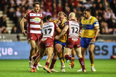 Tom Holroyd of Leeds Rhinos is tackled by Kruise Leeming of Wigan Warriors and Liam Farrell of Wigan Warriors during the Betfred Super League round 27 match Wigan Warriors vs Leeds Rhinos at The Brick Community Stadium, Wigan, United Kingdom 